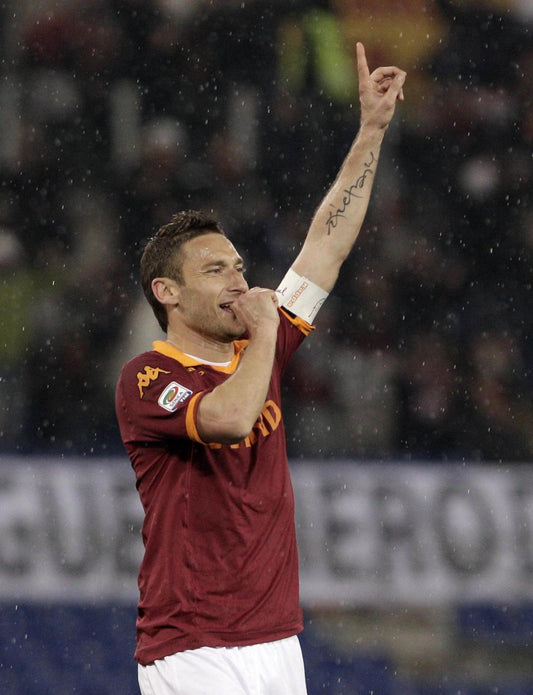 Francsceo Totti As Roma Captain while exulting in his iconi pose with a finger in the mouth after one of morfe than 300 goals scored in Seria A.