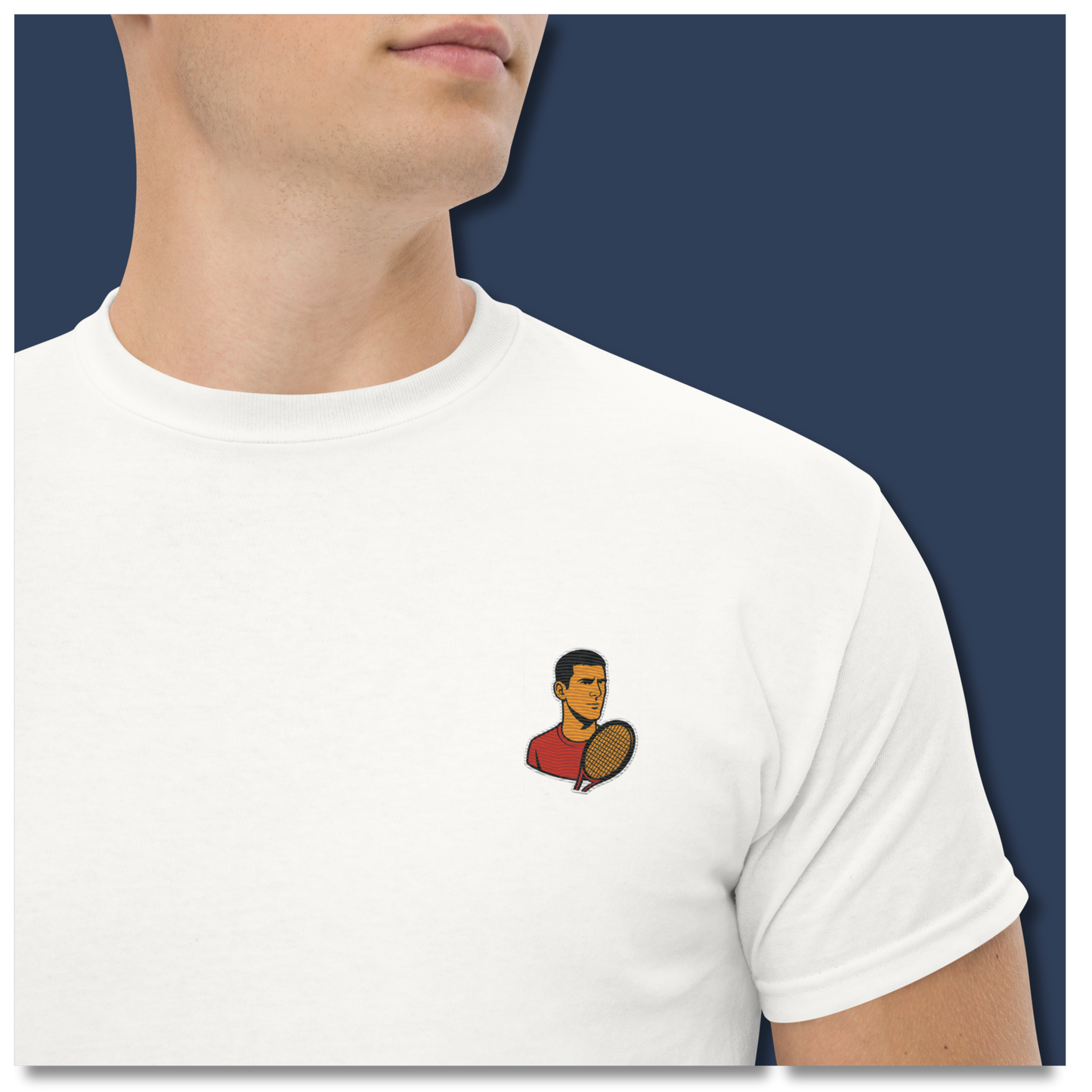 White cotton short sleeve t-shirt featuring a small, minimalist embroidered graphic design of tennis player Novak Djokovic in a red shirt holding a racket.