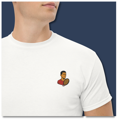 White cotton short sleeve t-shirt featuring a small, minimalist embroidered graphic design of tennis player Novak Djokovic in a red shirt holding a racket.