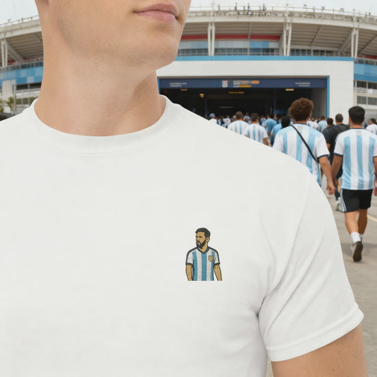 Men's (or Unisex) white cotton graphic tee featuring a small, retro-inspired embroidered patch/graphic of football player Lionel Messi in the Argentina (AFA) 'Albiceleste' jersey. GOAT, soccer, football, vintage style, Strength and Courage brand.