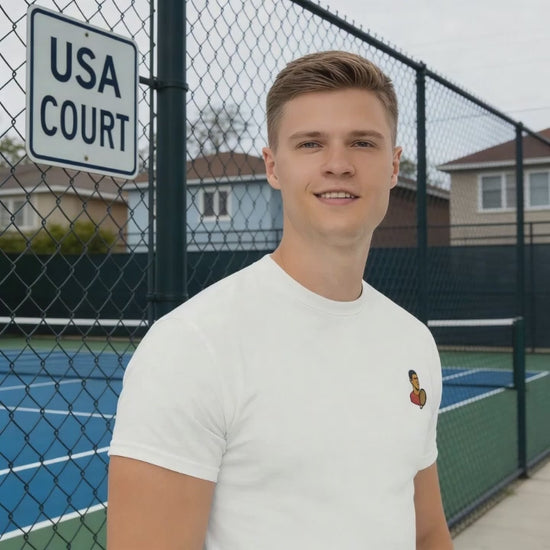 White cotton short sleeve t-shirt featuring a small, minimalist embroidered graphic design of tennis player Novak Djokovic in a red shirt holding a racket.